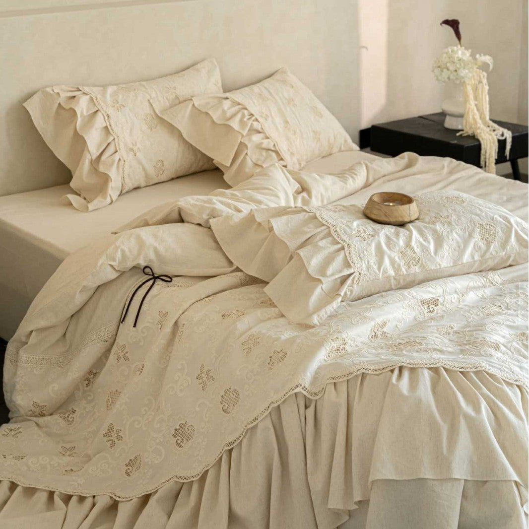 Romantic cotton bedding set in country house style with embroidered bedspread, ruffled bed skirt, and frill pillow.