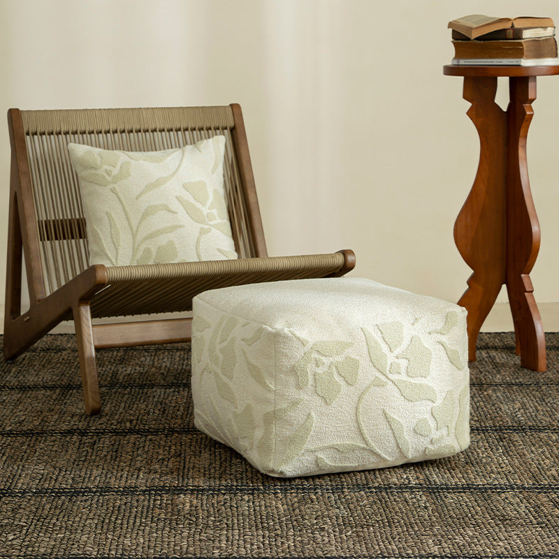 Square floor sitting pouf with textured bouclé surface and floral relief