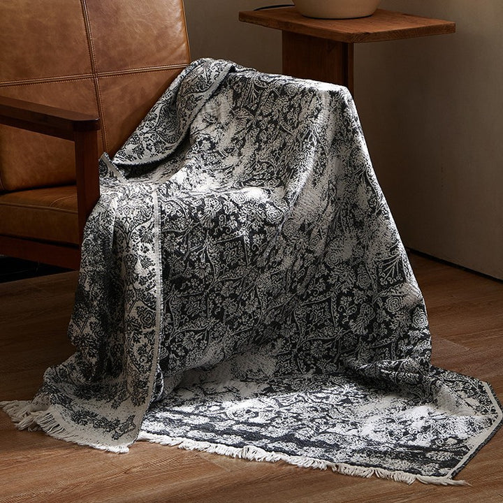 Large cozy living blanket made of cotton blend fabric with geometric jacquard pattern and fringed hem