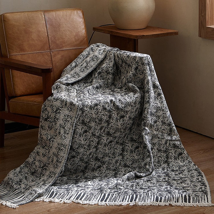 Large cozy living blanket made of cotton blend fabric with geometric jacquard pattern and fringed hem
