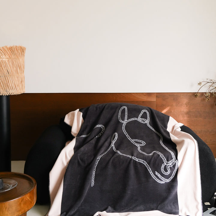 Throw blanket with embroidered cord motif and decorative stitching