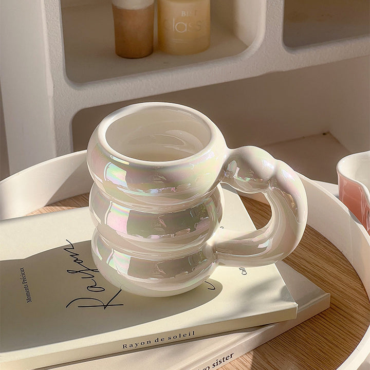 Sculptural ceramic mug with iridescent glaze and curved ring handle
