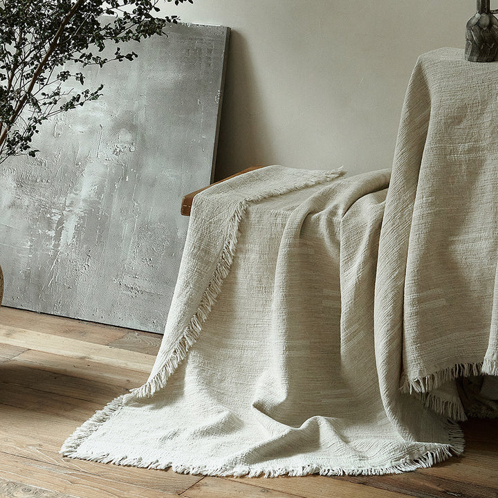 Massive wooden bed with upright slatted headboard and natural linen bedding