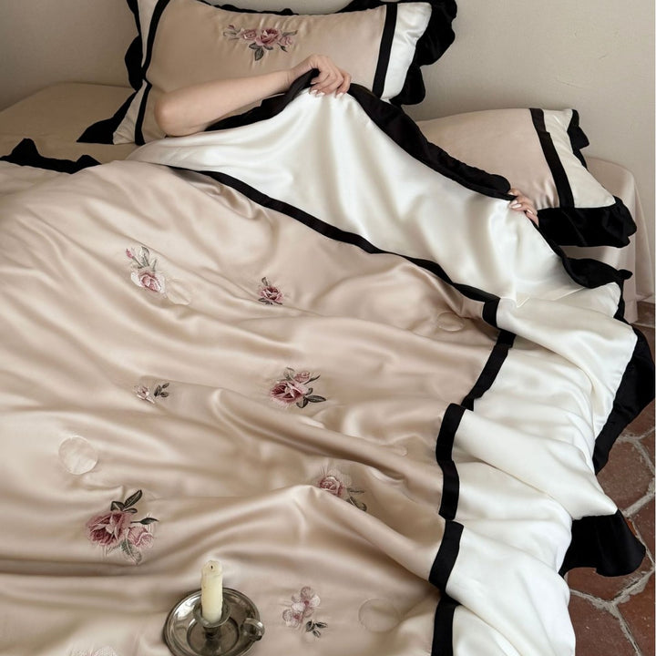 Satin duvet cover set with subtly embroidered roses, contrasting piping and ruffled hem