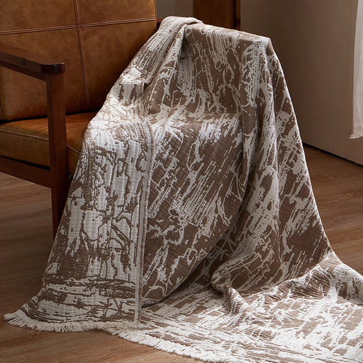 Large cozy living blanket made of cotton blend fabric with geometric jacquard pattern and fringed hem