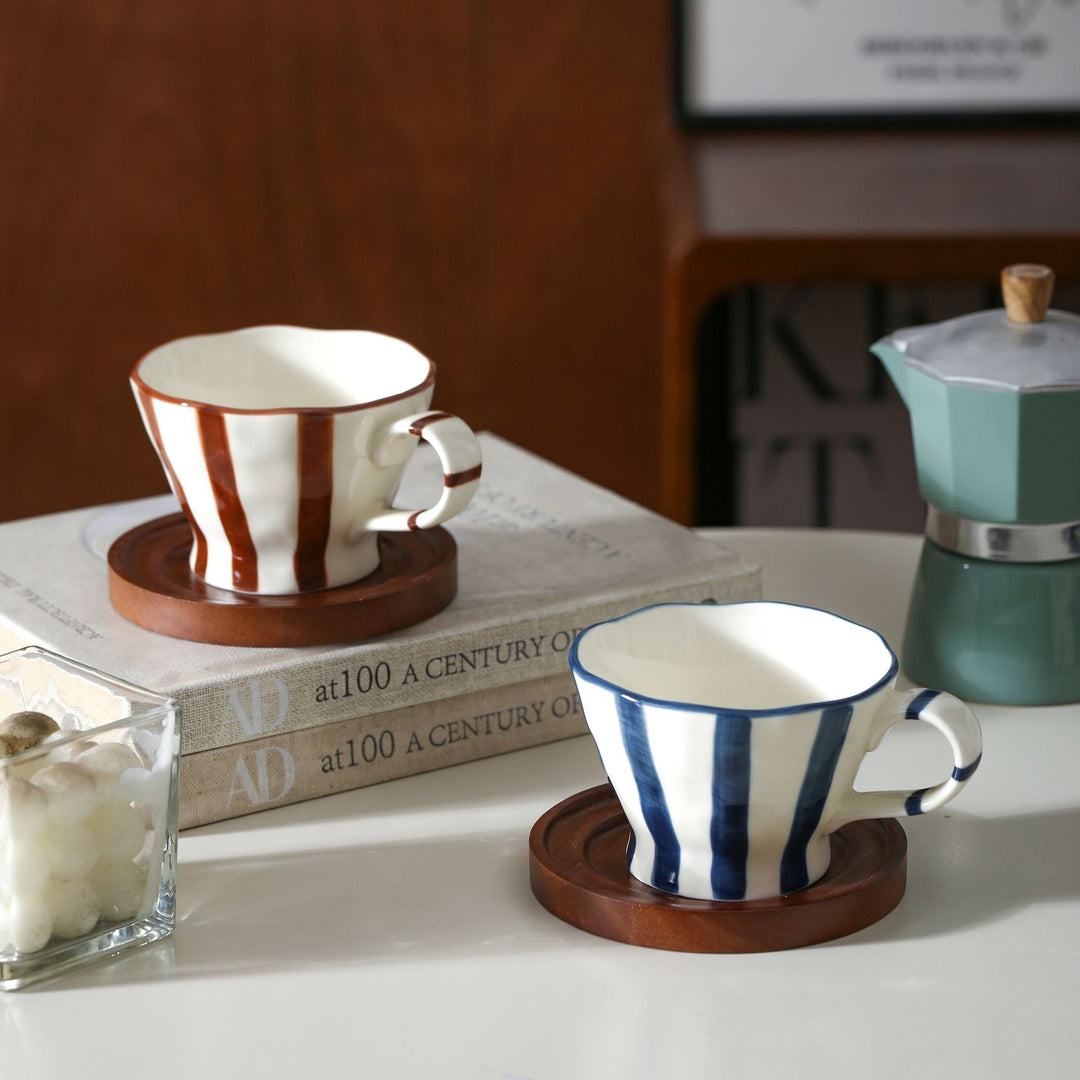Sculptural ceramic coffee cup with curved rim and distinctive stripe decor