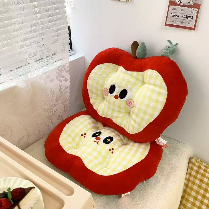 Padded children's seat cushion in apple shape with ergonomic seat recess and plush pendant