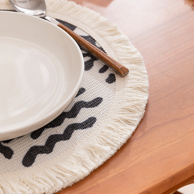Round woven placemat with fringes and abstract figure motif Kalsten