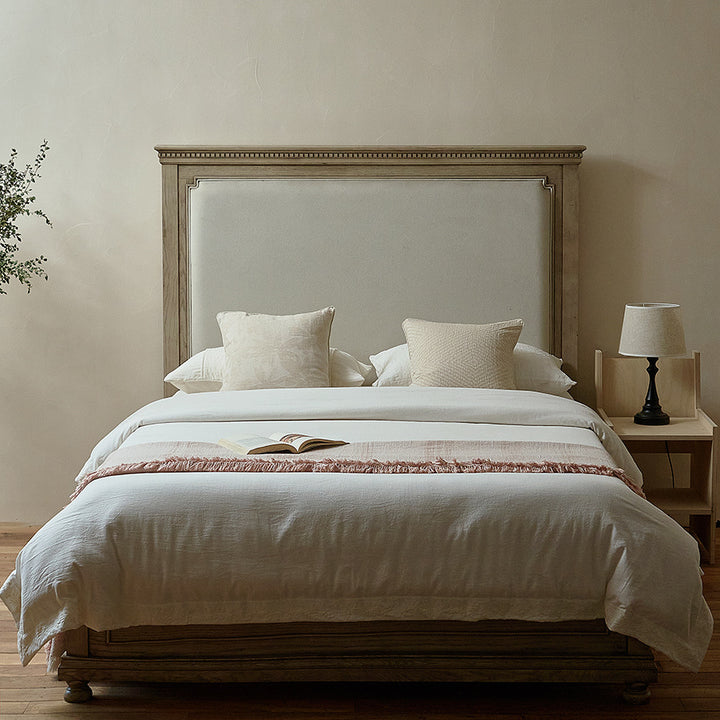 Massive wooden bed with upright slatted headboard and natural linen bedding