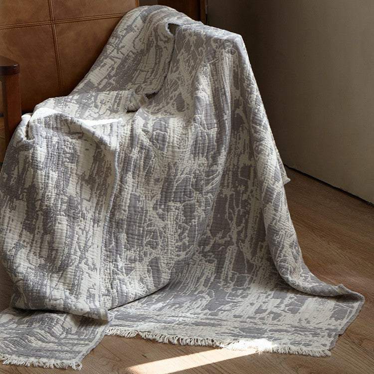 Large cozy living blanket made of cotton blend fabric with geometric jacquard pattern and fringed hem