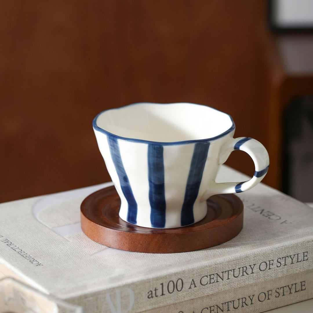 Sculptural ceramic coffee cup with curved rim and distinctive stripe decor