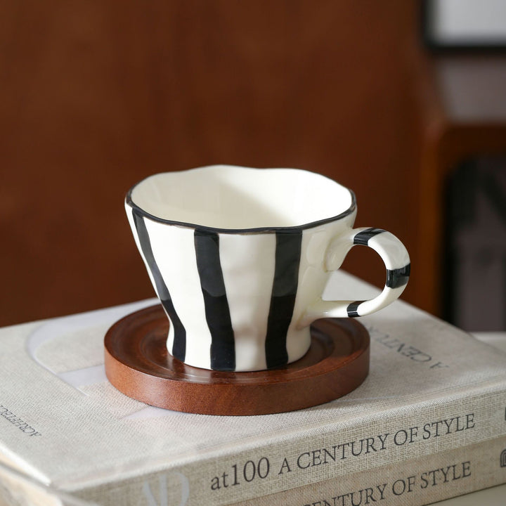 Sculptural ceramic coffee cup with curved rim and distinctive stripe decor