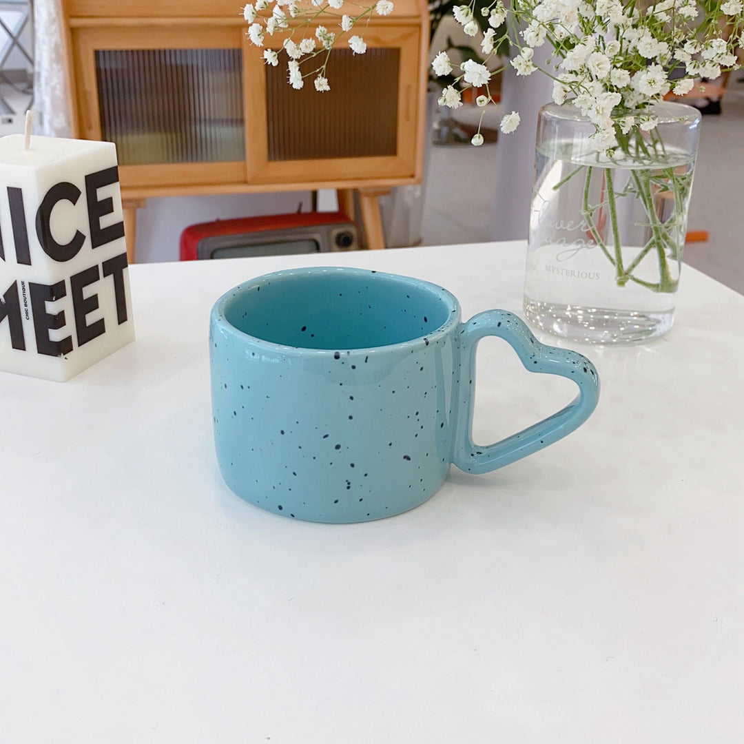 Ceramic mug with heart-shaped handle and speckle design
