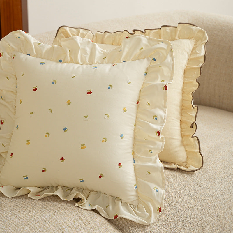 Decorative cushion with ruffles and embroidered flower pattern