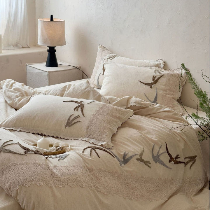 Home decor bedding set made of organic linen with hand-embroidered swallow motif and wavy hem
