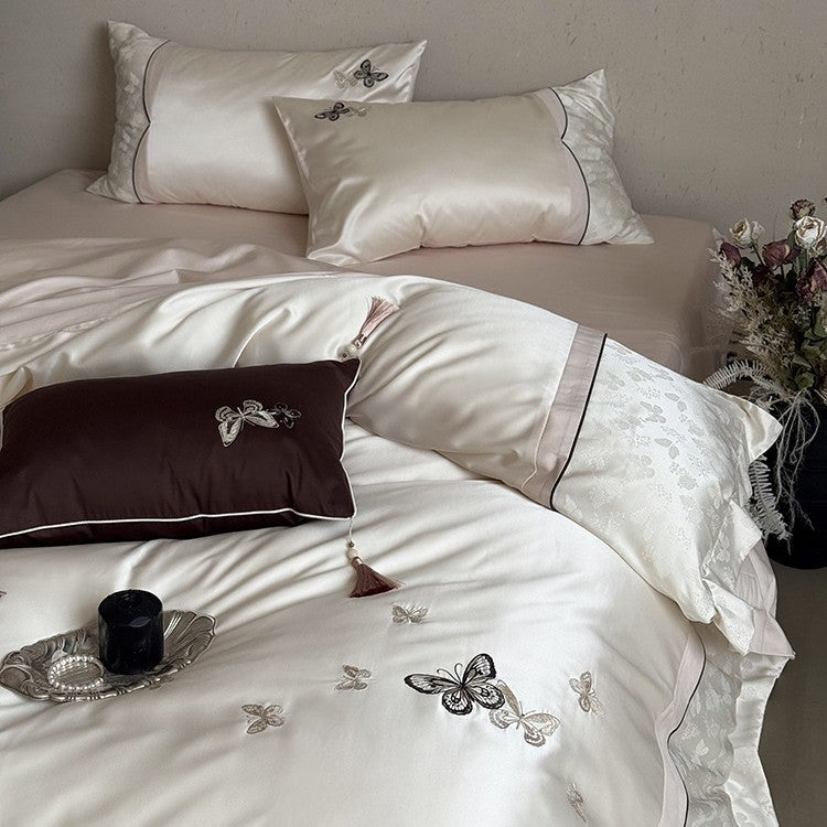 Luxurious satin bedding set with embroidered butterflies, decorative pillows, and tassels