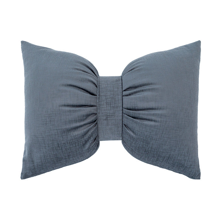 Bow-shaped decorative cushion with central band detail and structured fabric look