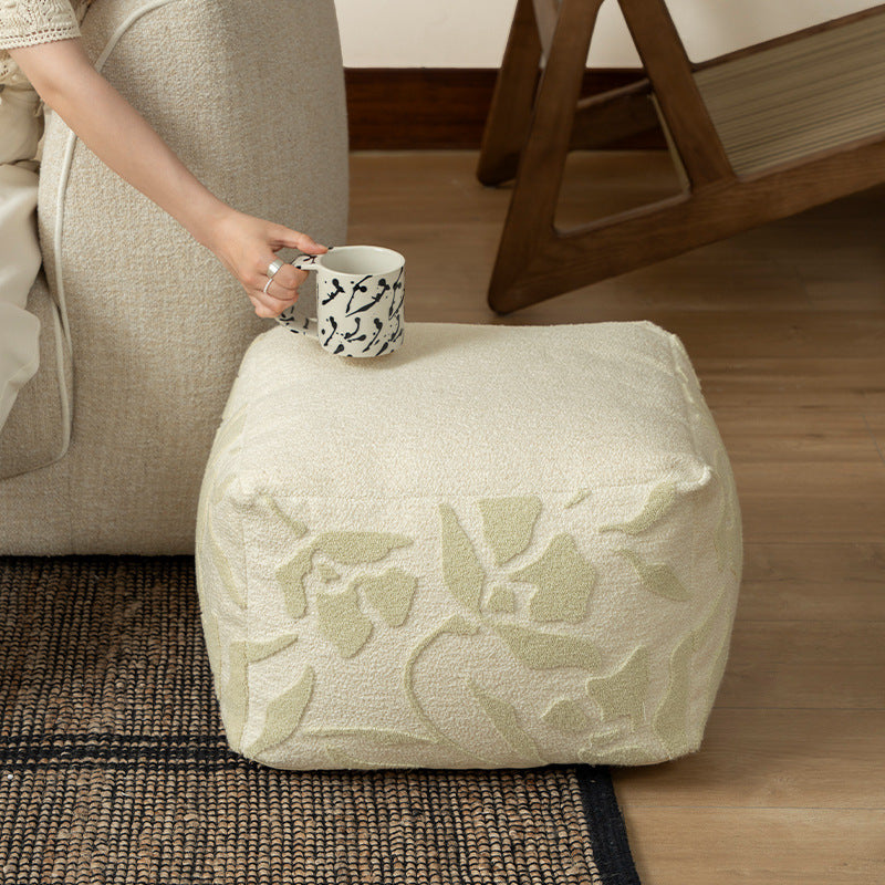 Square floor sitting pouf with textured bouclé surface and floral relief