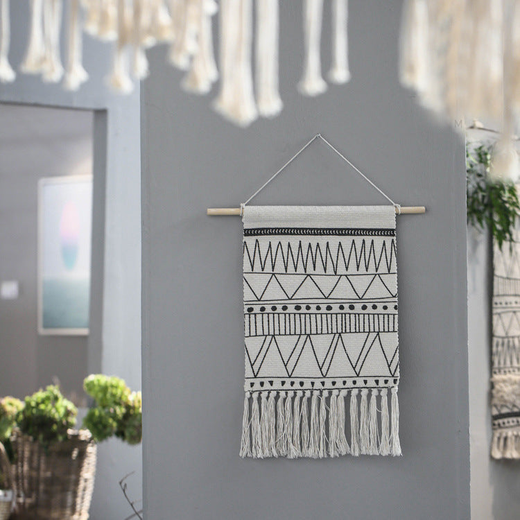 Woven wall hanging made of cotton blend with wooden rod, fringes and geometric ethnic pattern