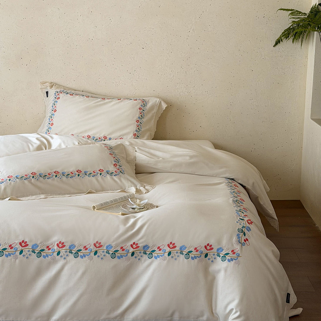 Embroidered cotton satin bed linen set with floral border and fine lace edge