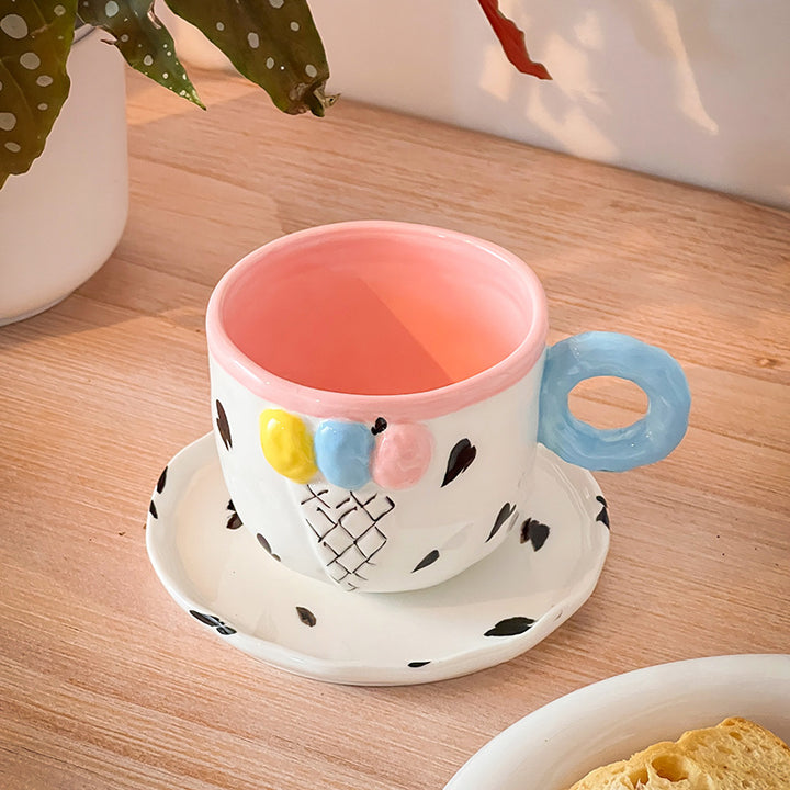 Playful handcrafted ceramic cup composition with saucer and pastel-colored round handle