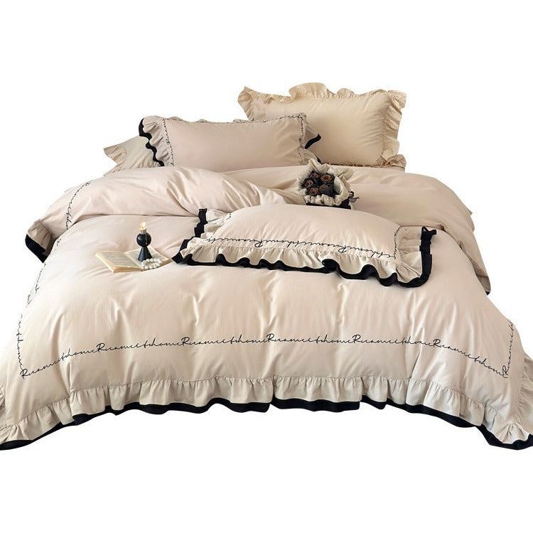Luxurious cotton satin bedding set with ruffle, contrasting piped trim, and calligraphic embroidery