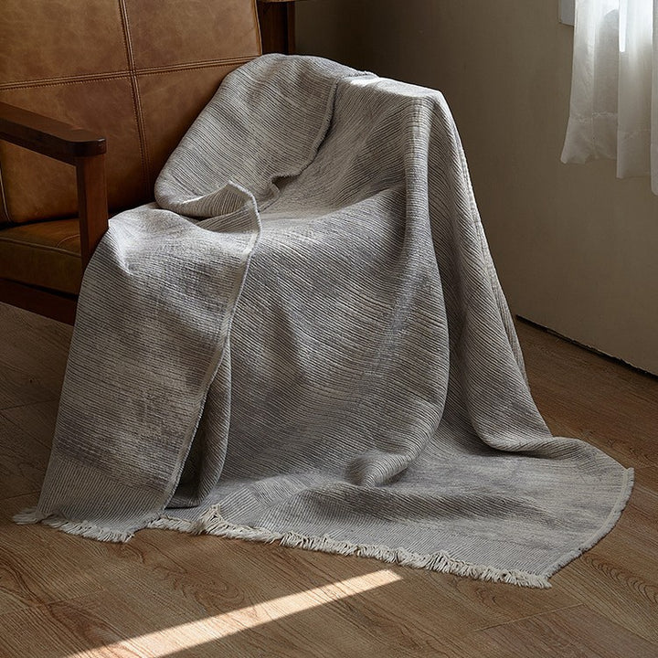 Large cozy living blanket made of cotton blend fabric with geometric jacquard pattern and fringed hem