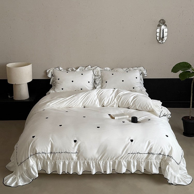 Luxurious cotton satin bedding set with ruffled trim, embroidered heart motifs, and calligraphic writing