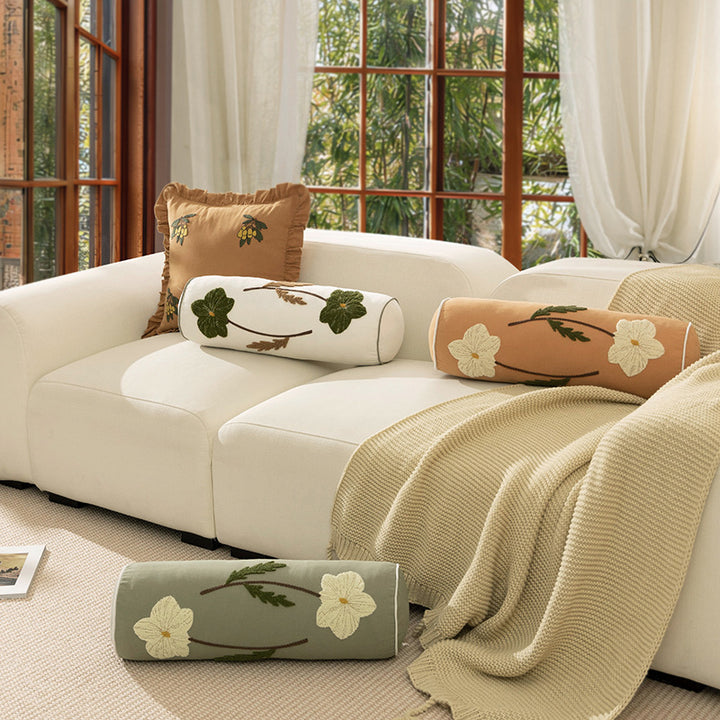 Bolster pillow with hand-stitched floral motif and decorative piping