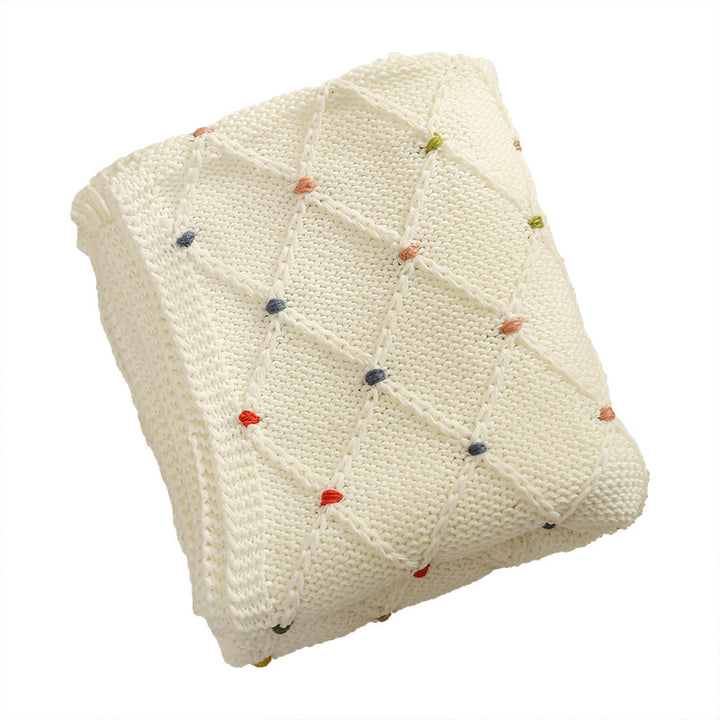 Chunky knitted cozy blanket with diamond pattern and colorful knots