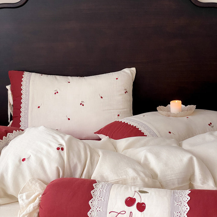 Country-style bedding set with cherry embroidery, lace trim, and decorative neck roll