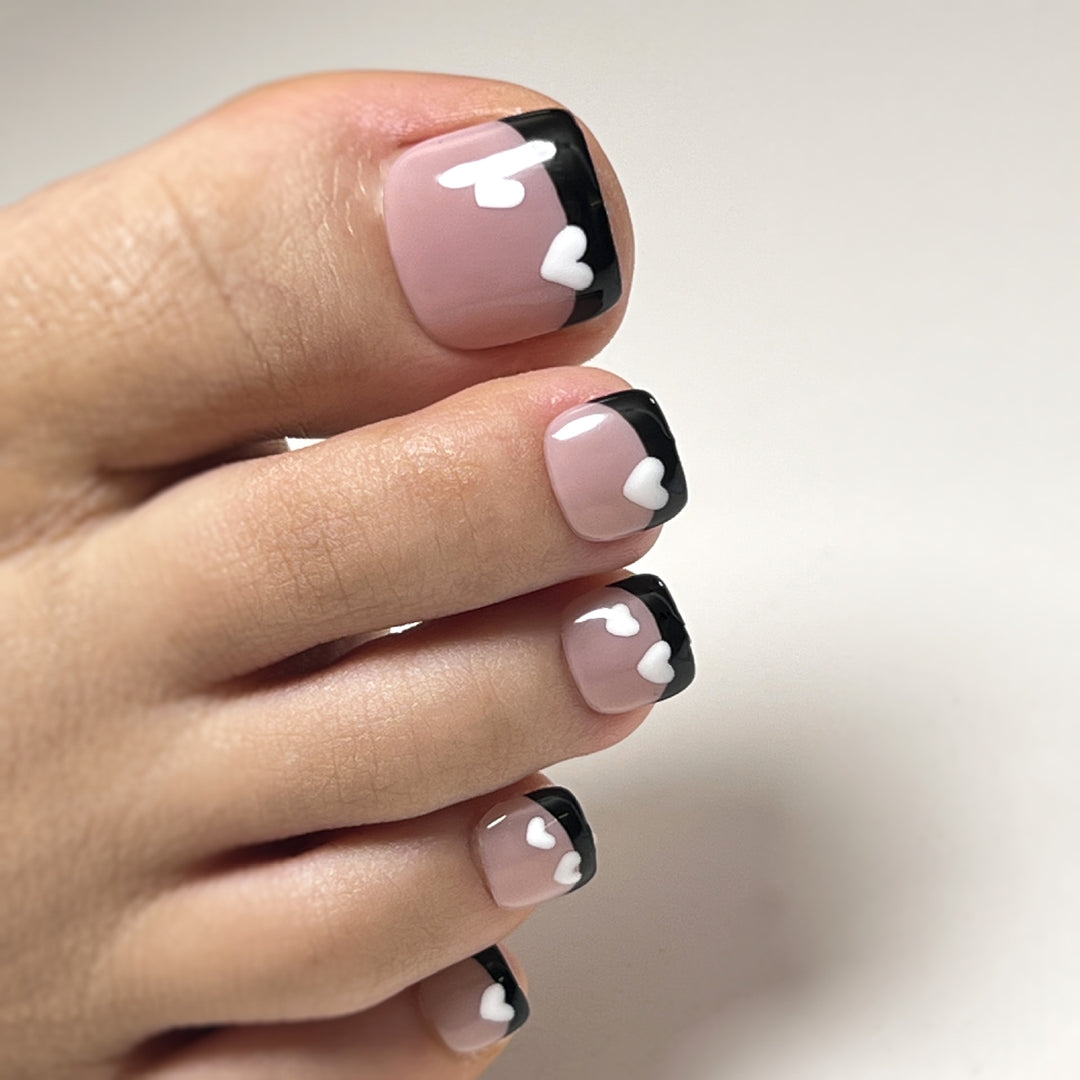 Artistic toenail design with heart motifs and modern black-and-white design Kalsten