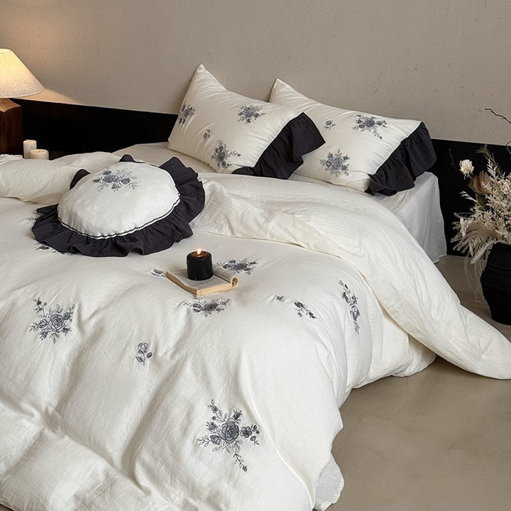 Cotton muslin bedding set with embroidered rose emblems and fine ruffle