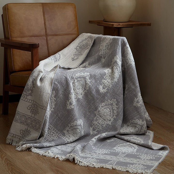 Large cozy living blanket made of cotton blend fabric with geometric jacquard pattern and fringed hem