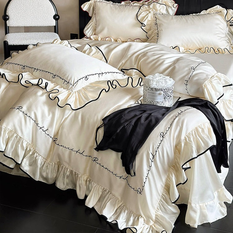 Luxurious cotton satin bedding set with ruffled flounces, contrasting piping & calligraphic embroidery