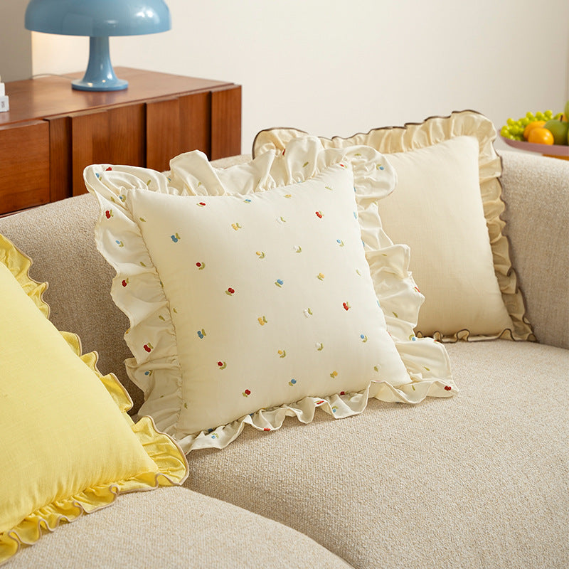 Decorative cushion with ruffles and embroidered flower pattern