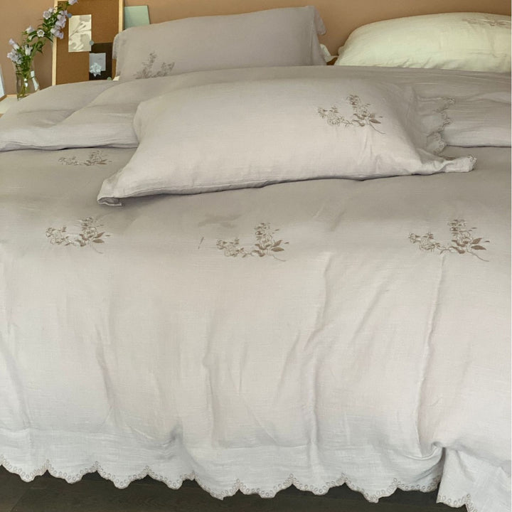 Linen look bedding set with floral embroidery and wavy hem