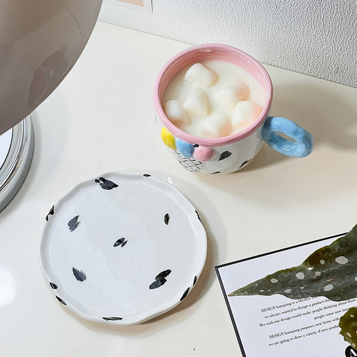Playful handcrafted ceramic cup composition with saucer and pastel-colored round handle