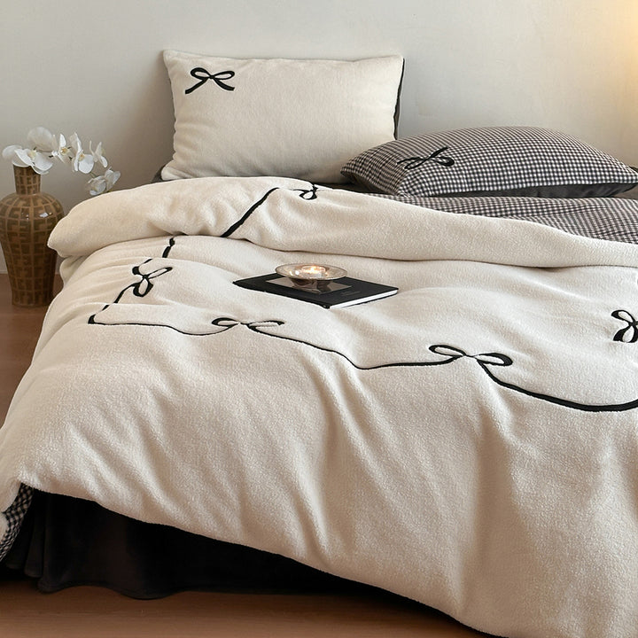 Reversible microfiber bedding set with plush surface, pom-pom corners, and paw embroidery