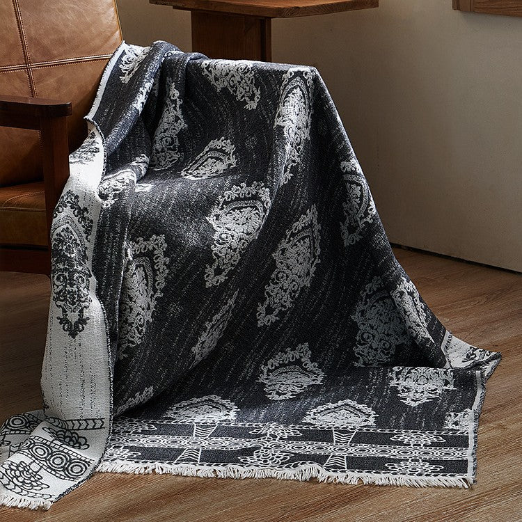 Large cozy living blanket made of cotton blend fabric with geometric jacquard pattern and fringed hem