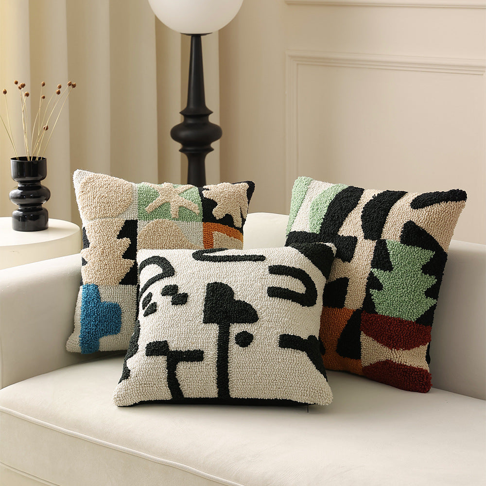 Hand-tufted decorative cushion with abstract graphic design and textured cotton surface