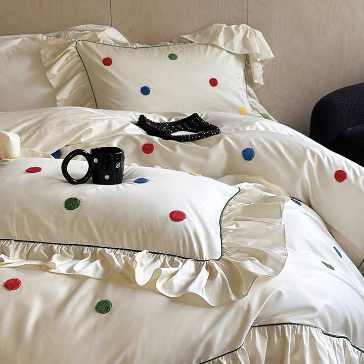 Bedding set with embroidered dots, decorative ruffles, and fine piping