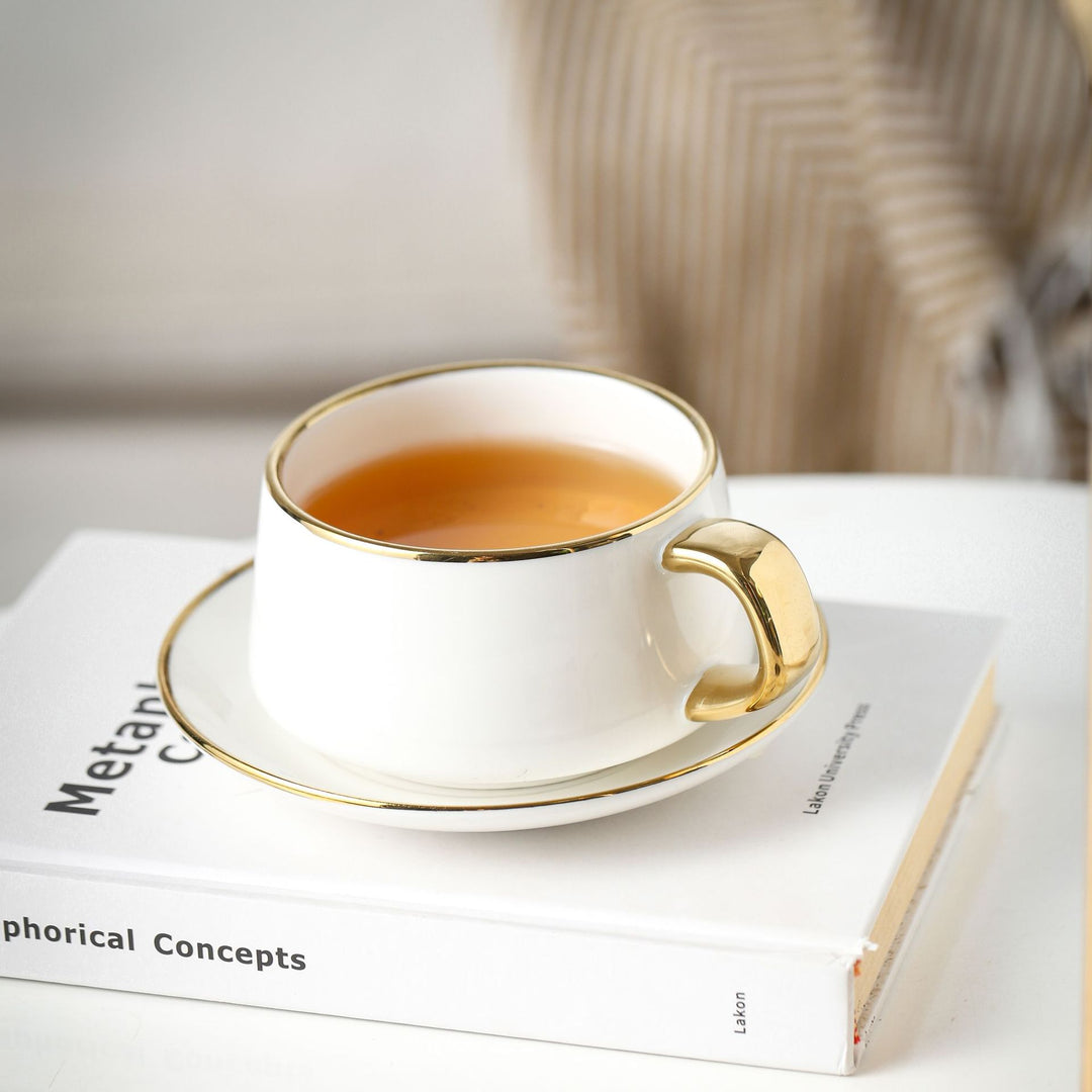 Elegant porcelain cup with saucer and sculptural gold handle