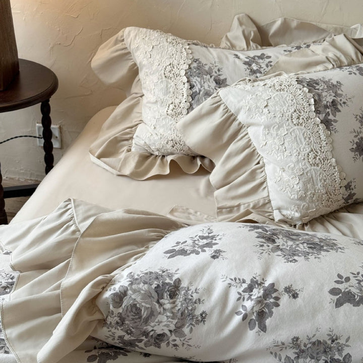 Bedding set in French country house style with lace trim, ruffled bed skirt, and subtle toile floral design