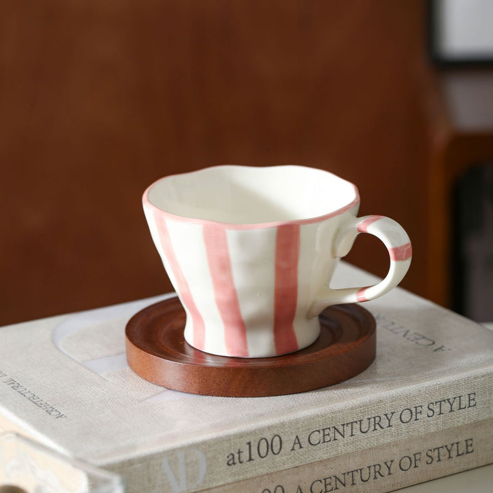 Sculptural ceramic coffee cup with curved rim and distinctive stripe decor