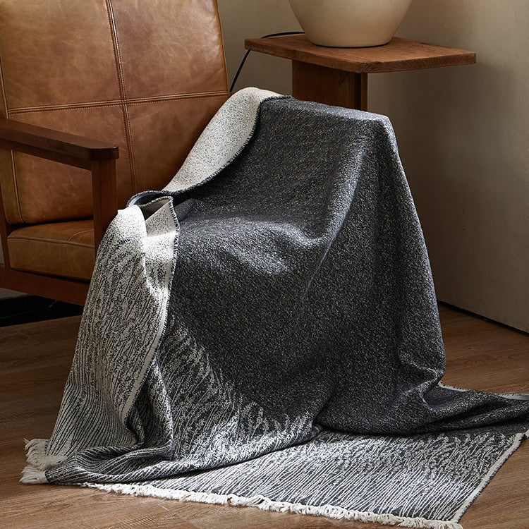 Large cozy living blanket made of cotton blend fabric with geometric jacquard pattern and fringed hem