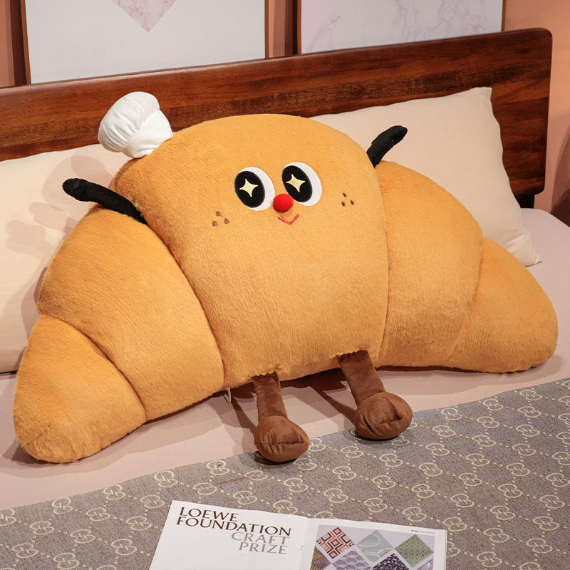Large cuddly plush pillow in croissant shape with cute cartoon face