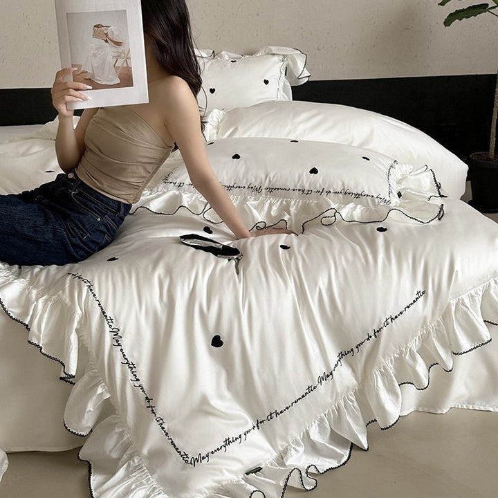 Luxurious cotton satin bedding set with ruffled trim, embroidered heart motifs, and calligraphic writing