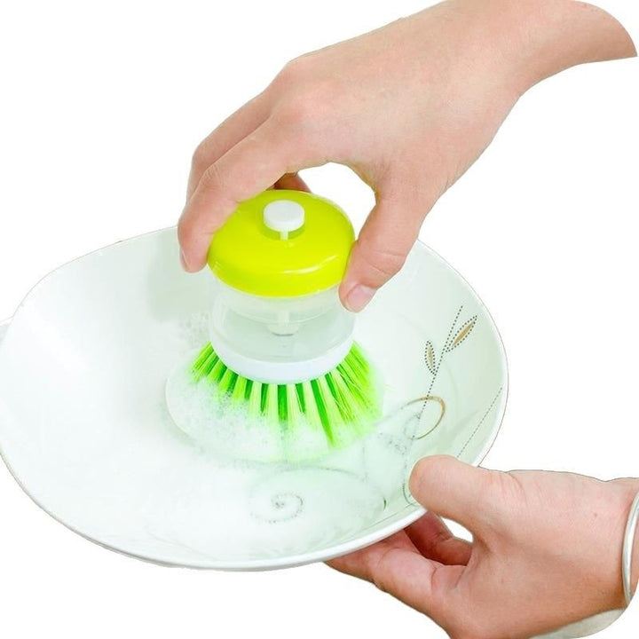 Dish brush with soap dispenser for pressing